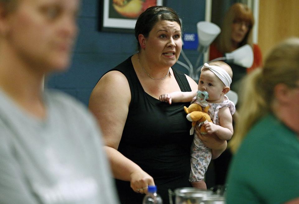 In this Aug. 22, 2019 photo, Jessica Moloney, holding her 6-month-old daughter Amelia, expresses her displeasure at a meeting at Highland High School in Marengo, Ohio, about how the school board handled a recent incident where a child had access to a gun, pointed it at another student, and that parents weren't informed. Schools across the country have faced a backlash for favoring privacy over telling parents when there are threats in their children’s classrooms. Safety experts advise schools to tell parents as much as they can as soon as they can about threats. (Fred Squillante/The Columbus Dispatch via AP)