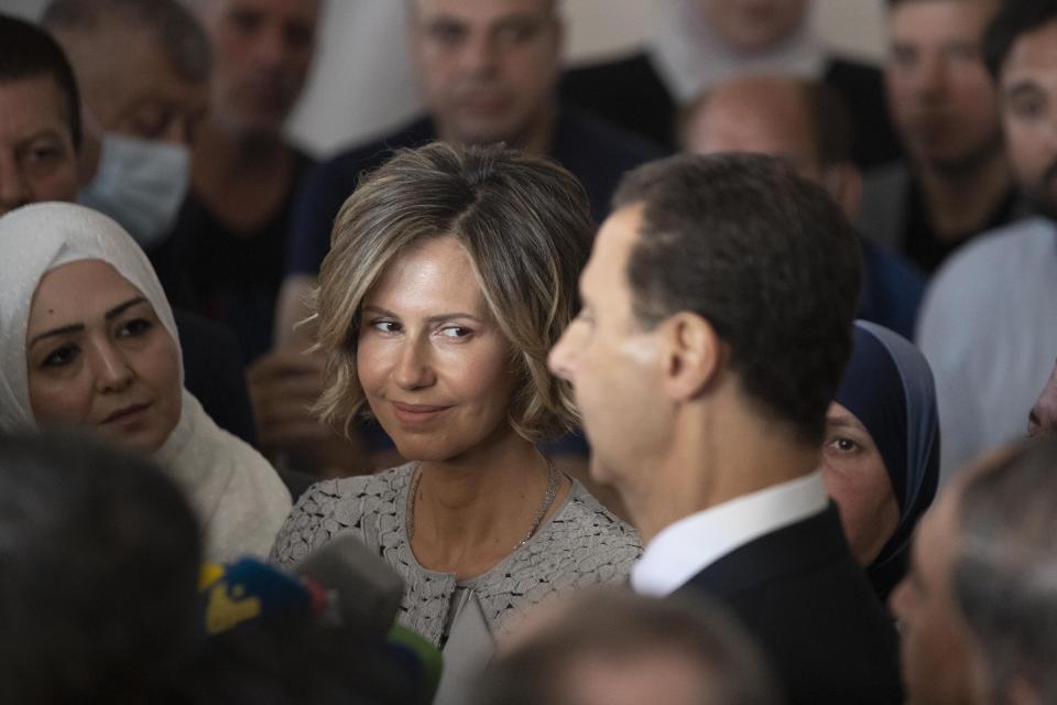 Syria's first lady Asma Assad, left, listens to her husband Syrian President Bashar Assad as he speaks to the media after they vote at a polling station during the Presidential elections in the town of Douma, in the eastern Ghouta region, near the Syrian capital Damascus, Syria, Wednesday, May 26, 2021. Syrians headed to polling stations early Wednesday to vote in the second presidential elections since the deadly conflict began in the Arab country. (AP Photo/Hassan Ammar)