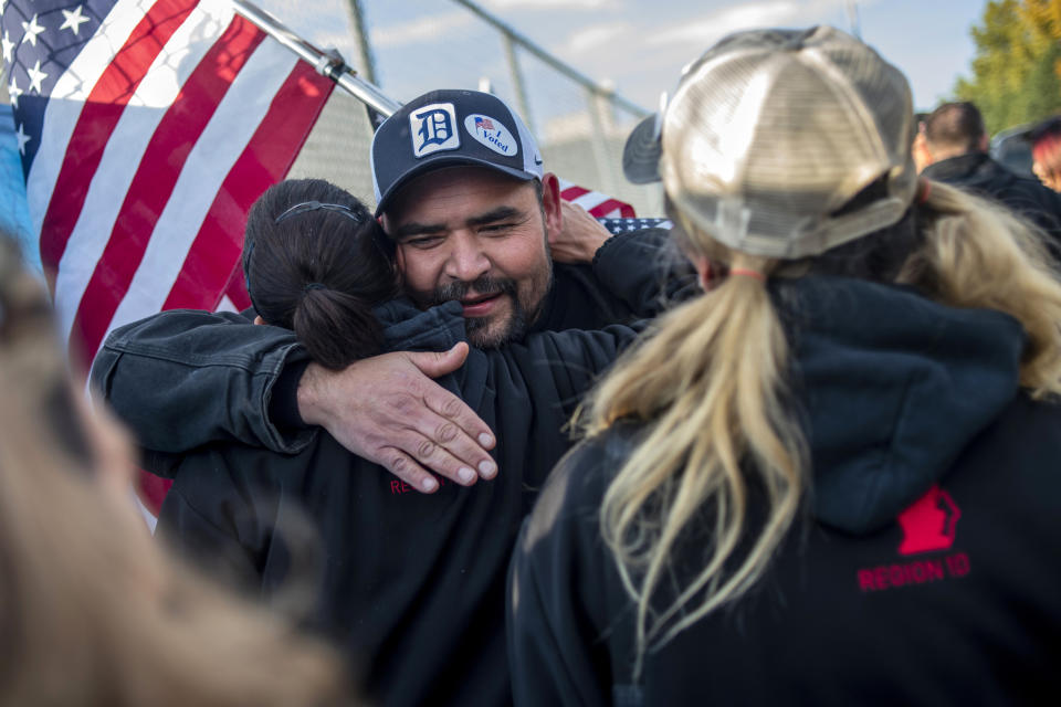 Saginaw resident Michael Perez and other members celebrate during the 40th and final day of the United Auto Workers strike against General Motors outside of the Flint Assembly Plant, Friday, Oct. 25, 2019, in Flint, Mich. Striking General Motors factory workers are putting down their picket signs after approving a new contract that will end a 40-day strike that paralyzed the company's U.S. production. (Jake May/MLive.com/The Flint Journal via AP)
