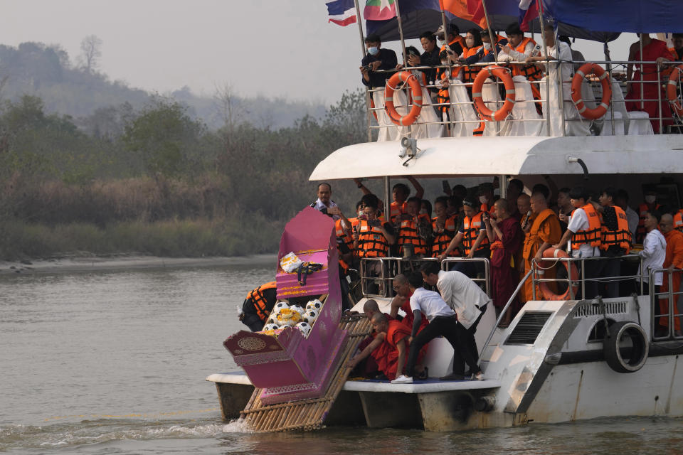 Family members, accompanied by monks and fellow mourners, release the ashes of Duangphet Phromthep in a makeshift boat along with soccer balls and some of his prized possessions into the Mekong River in Chiang Rai Province Thailand, Monday, March 6, 2023. Duangphet was one of the 12 boys rescued from a flooded cave in 2018. He died in the U.K. last month. (AP Photo/Sakchai Lalit)