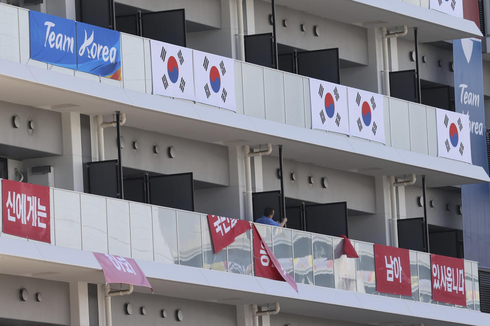 Banners with the words "I still have the support of 50 million Korean people," are removed from balconies at the the Olympic athletes' village in Tokyo Saturday, July 17, 2021. South Korea's Olympic Committee said Saturday it has removed banners at the Olympic athletes' village in Tokyo that called up a 16th-century war between Korea and Japan after the International Olympic Committee ruled it was provocative. (Jin Sung-chul/Yonhap via AP)