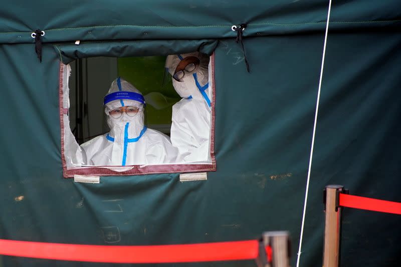 Medical workers in protective suits wait for rescue workers following the coronavirus disease (COVID-19) outbreak, at the Hushan gold mine where workers were trapped underground after the January 10 explosion, in Qixia