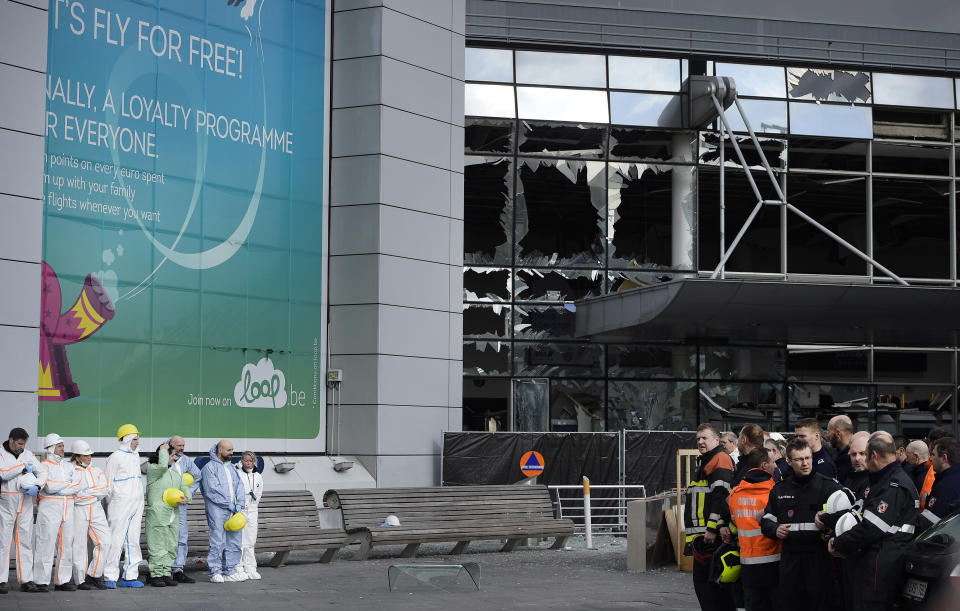 FILE - In this March 23, 2016 file photo, forensic officers and firemen stand in front of the damaged terminal at Zaventem Airport in Brussels. One year after the March 22, 2016 Brussels attacks, the city's physical scars may have healed, but the pain is still apparent beneath the surface. (Yorick Jansens, Pool photo via AP, File)