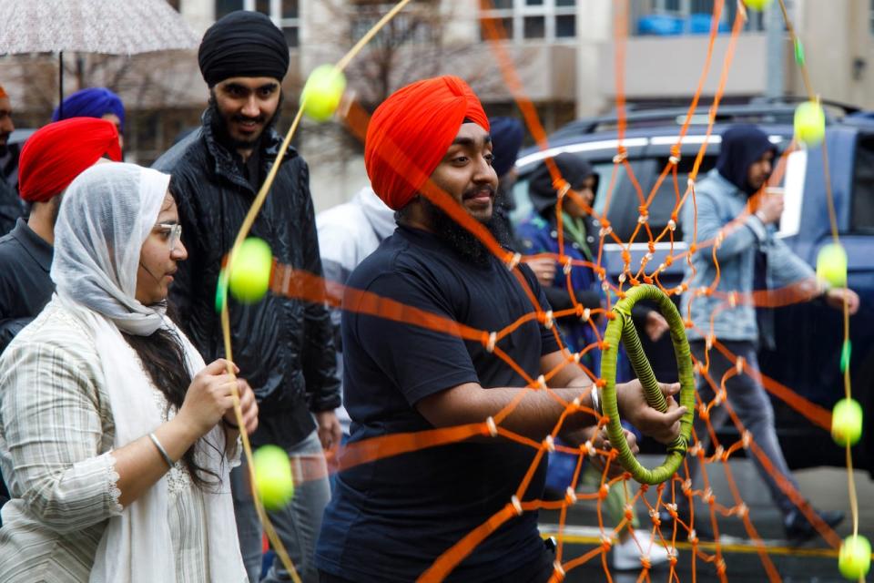 People celebrate Vaisakhi, also known as Khalsa Day, during a parade in downtown Toronto on April 30, 2023. See man in parade spinning a wheel or chakkar. 