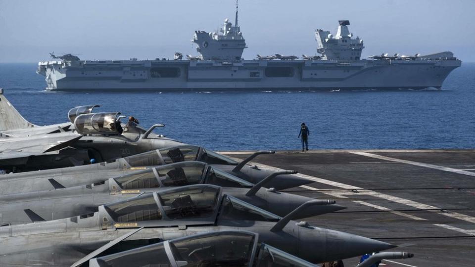 French navy Rafale jet fighters sit on the bridge of the French aircraft carrier Charles de Gaulle with the UK Royal Navy's aircraft carrier HMS Queen Elizabeth in the background during the Navy exercise "Gallic strike" off the coast of Toulon, south-eastern France on June 3, 2021.