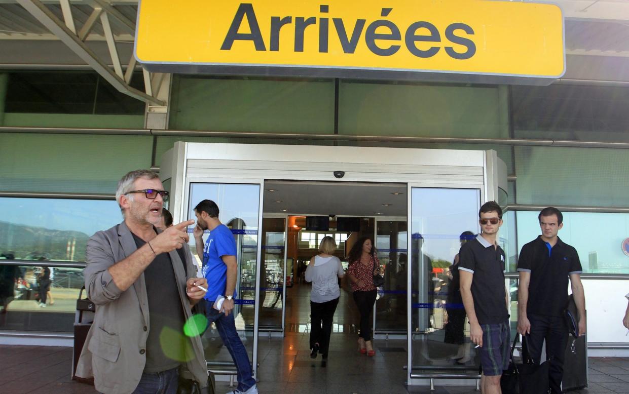 A man smokes outside the arrivals gate