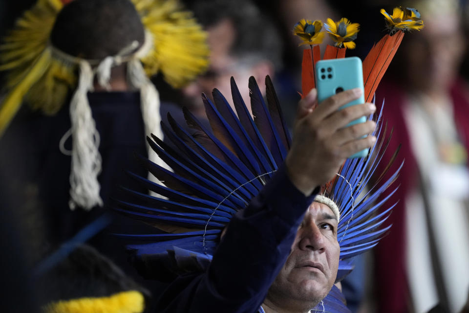 Un indígena toma una fotografía con su celular mientras espera el inicio de la ceremonia de clausura de la primera reunión ordinaria del Consejo Nacional para Políticas Indígenas, en Brasilia, Brasil, el 18 de abril de 2024. (AP Foto/Eraldo Peres)