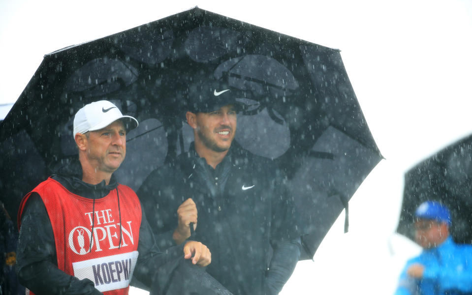 Brooks Koepka of the United States shelters under an umbrella with caddie, Ricky Elliot on the 3rd hole during the first round of the 148th Open Championship held on the Dunluce Links at Royal Portrush Golf Club on July 18, 2019 in Portrush, United Kingdom. (Photo by Andrew Redington/Getty Images)