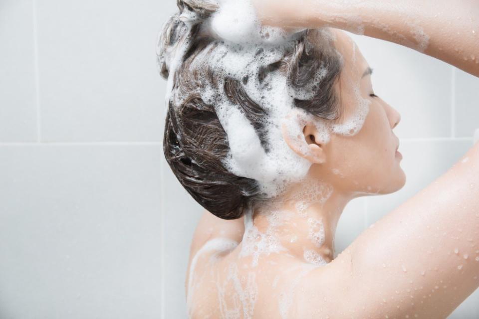 woman washing hair in the shower with shampoo