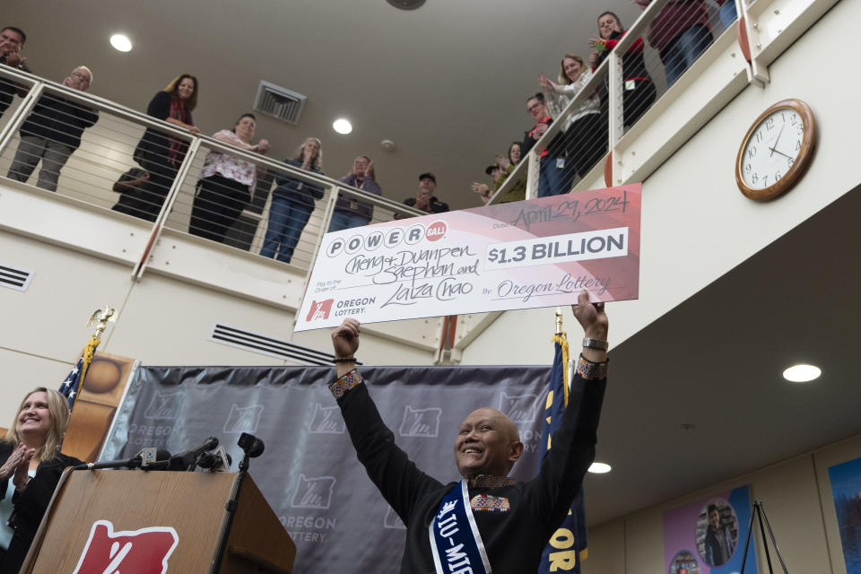 Cheng "Charlie" Saephan holds display check above his head after speaking during a news conference where it was revealed that he was one of the winners of the $1.3 billion Powerball jackpot at the Oregon Lottery headquarters on Monday, April 29, 2024, in Salem, Ore. (AP Photo/Jenny Kane)