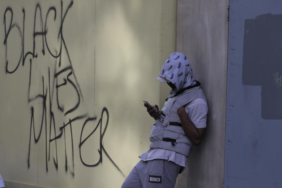 A member of Black Lives Matter movement, uses his mobile phone following a protest in central London, Saturday, June 13, 2020. British police have imposed strict restrictions on groups that protested in London Saturday in a bid to avoid violent clashes between protesters from the Black Lives Matter movement, as well as far-right groups that gathered to counter-protest.(AP Photo/Kirsty Wigglesworth)