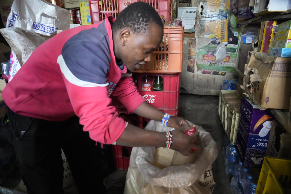 Joseph Kuraru, a 26 year-old kiosk owner in Nairobi, Kenya, removes sugar from a sack to serve to a customer, Friday, Oct 27, 2023. The amount of sugar milled in Kenya fell steadily from June to August. To compensate, monthly imports doubled from September to October. Meanwhile, a 50-kilogram (110 pounds) bag of local sugar doubled in price, said Kuraru. (AP Photo/Sayyid Abdul Azim)