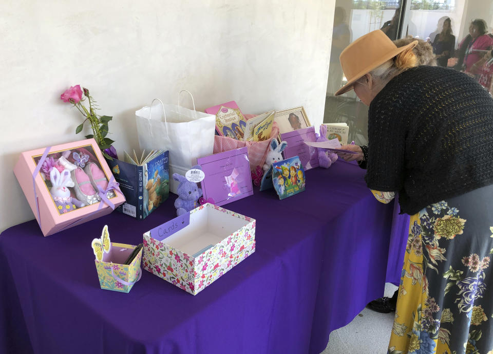 A woman looks a display of mementos at the funeral service for Trinity Love Jones, the 9-year-old whose body was found this month stuffed in a duffel bag along an equestrian trail, at St. John Vianney Catholic Church in Hacienda Heights, Calif., Monday, March 25, 2019. The Hacienda Heights community where her body was found had embraced the child in death during the days she remained unidentified. A park worker found Trinity on March 5. A huge memorial sprang up at the site as community members heard about the case. She was identified the following weekend and prosecutors have since filed murder charges against her mother and the mother's boyfriend. (AP Photo/John Rogers)