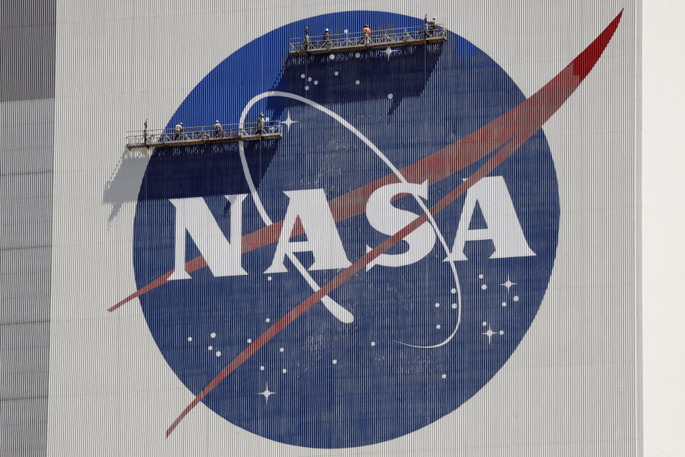 ARCHIVO - Trabajadores en andamios repintan el logo de la NASA en el Centro Espacial Kennedy, en Cabo Cañaveral, Florida, el 20 de mayo de 2020. (AP Foto/John Raoux, Archivo)