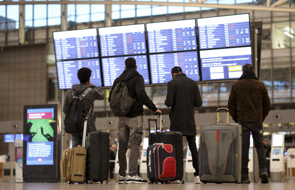 Travelers look at a display board at the airport in Hamburg, Germany, Tuesday, Jan. 15, 2019. Flights across Germany are facing disruption after security staff at eight airports went on strike over pay. (Christian Charisius/dpa via AP)