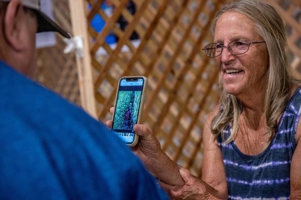 Sue Crews shows a family photo while chatting with a visitor at her Mendocino Family Farms booth at the California State Fair on Thursday. “We are unfairly picked on because we are growing cannabis. We are almost broke because of all the things we have to pay,” said Crews.