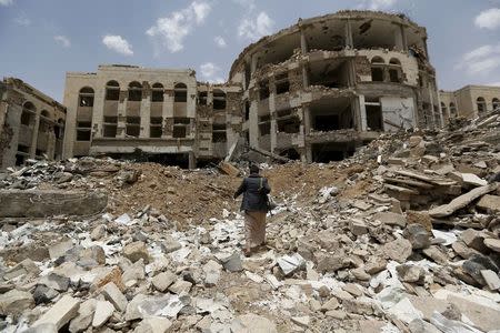 A Houthi militant walks in front of a government compound, destroyed by recent Saudi-led air strikes, in Yemen's northwestern city of Amran July 27, 2015. REUTERS/Khaled Abdullah