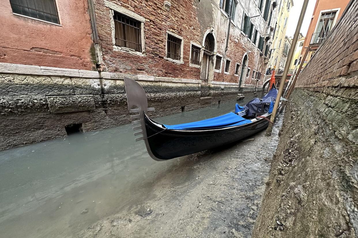 Gondola is docked on a dry canal during a low tide in Venice, Italy