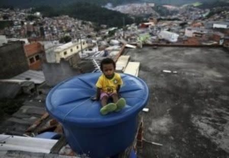 Igor, 6, sits on a water container, on the roof of his house in Brasilandia slum, in Sao Paulo, Brazil, February 10, 2015. REUTERS/Nacho Doce