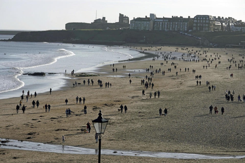 People walking on Tynemouth beach, as England continues a four week national lockdown to curb the spread of coronavirus, in Tyne and Wear, England, Sunday, Nov. 22, 2020. (Owen Humphreys/PA via AP)