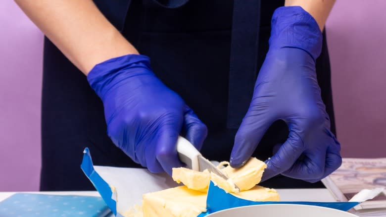 Person with gloves cutting butter