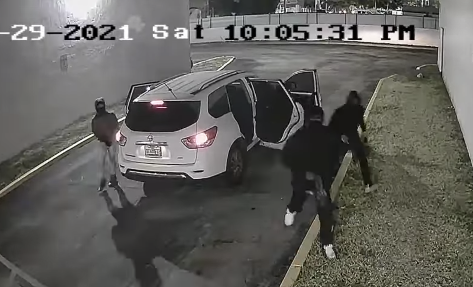 A CCTV still of the three suspects of a Miami birthday party concert shooting leaving a white SUV, carrying guns.