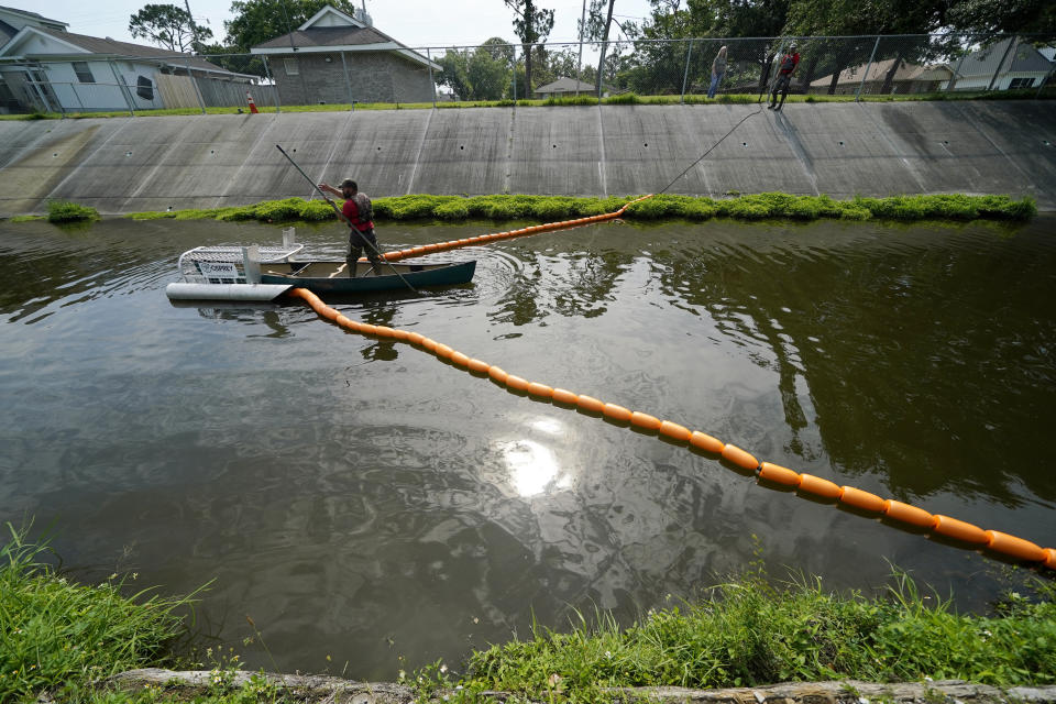 Employees of Osprey Initiative install a Litter Gitter to help collect trash before it can travel into larger bodies of water, in Metairie, La., Thursday, May 19, 2022. Many novel devices are being used or tested worldwide to trap plastic trash in rivers and smaller streams before it can get into the ocean. (AP Photo/Gerald Herbert)