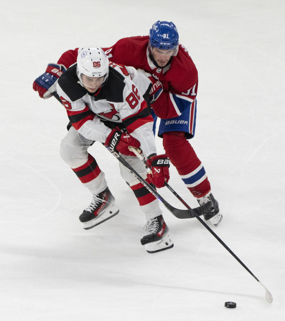 Montreal Canadiens' Sean Monahan (91) and New Jersey Devils' Jack Hughes (86) compete for the puck during the second period of an NHL hockey game Tuesday, Oct. 24. 2023, in Montreal. (Christinne Muschi/The Canadian Press via AP)