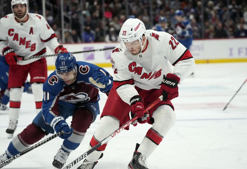 Carolina Hurricanes defenseman Brett Pesce, right, collects the puck as Colorado Avalanche center Andrew Cogliano defends during the first period of an NHL hockey game Saturday, Nov. 12, 2022, in Denver. (AP Photo/David Zalubowski)