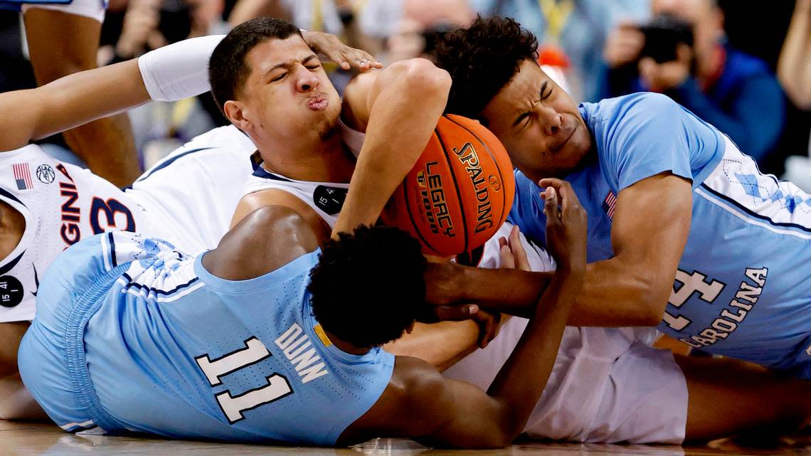 North Carolina’s D’Marco Dunn (11) and Puff Johnson (14) fight for the loose ball with Virginia’s Kadin Shedrick (21) during the first half of UNC’s game against Virginia in the quarterfinals of the ACC Men’s Basketball Tournament in Greensboro, N.C., Thursday, March 9, 2023.