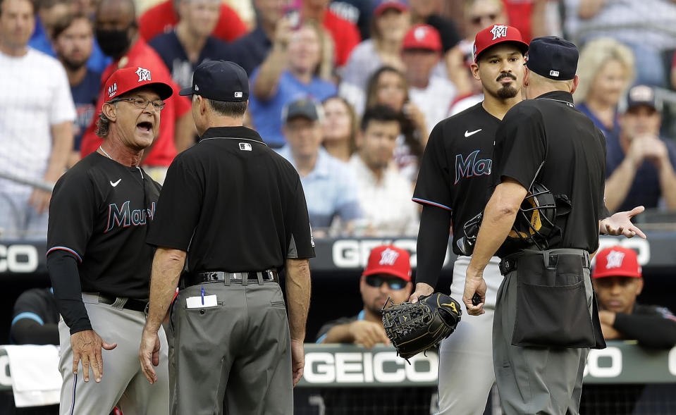 Miami Marlins manager Don Mattingly, left, and pitcher Pablo Lopez, second from right, speak with umpires after both were ejected in the first inning of a baseball game against the Atlanta Braves ,Friday, July 2, 2021, in Atlanta. Marlins pitcher Pablo Lopez hit Braves' Ronald Acuna Jr. with the first pitch of the game. (AP Photo/Ben Margot)