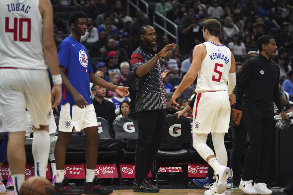 Los Angeles Clippers forward Kawhi Leonard, center, who is sitting out due to injury, high-fives guard Luke Kennard during the first half of an NBA basketball game against the New Orleans Pelicans on Sunday, Oct. 30, 2022, in Los Angeles, Calif. (AP Photo/Allison Dinner)