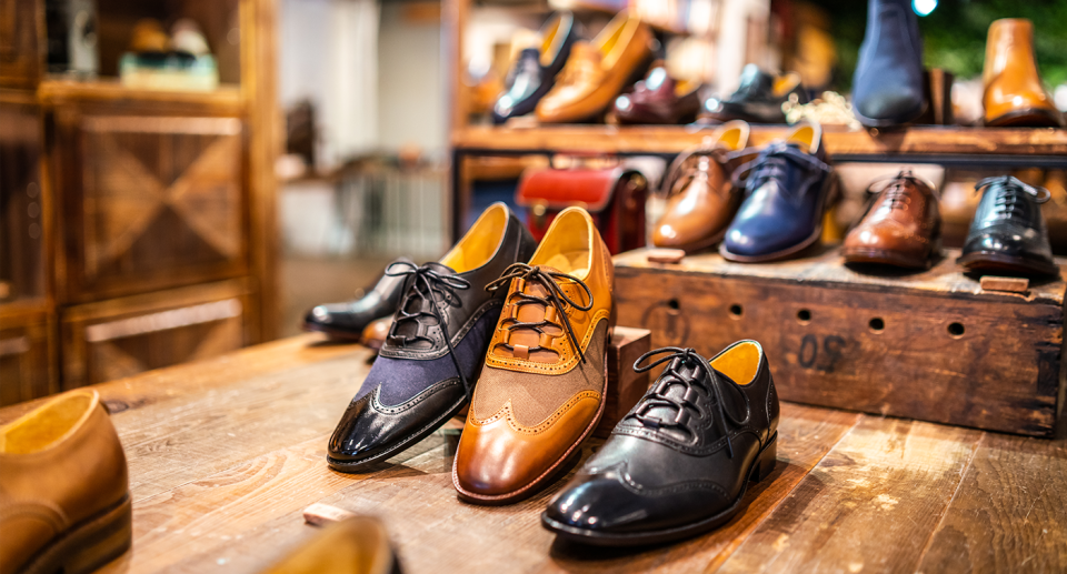 A number of high-end leather shoes on wooden displays.