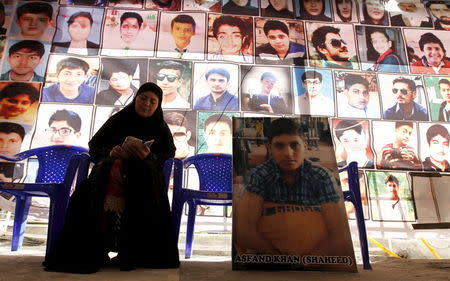 Shahana Ajoon, mother of Asfand Khan, sits beside a picture of her son in Peshawar, Pakistan December 11, 2015. REUTERS/Caren Firouz