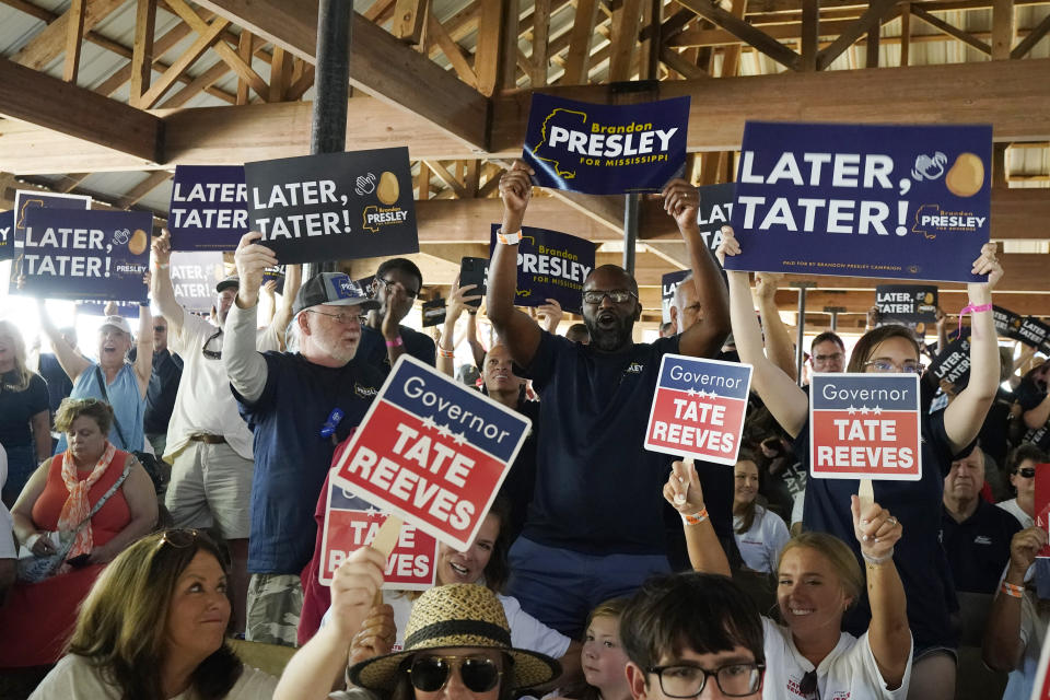 Contrasting groups of supporters for the incumbent Mississippi Gov. Tate Reeves and Democrat Brandon Presley wave their respective candidates' signs at the Neshoba County Fair in Philadelphia, Miss., Thursday, July 27, 2023. (AP Photo/Rogelio V. Solis)
