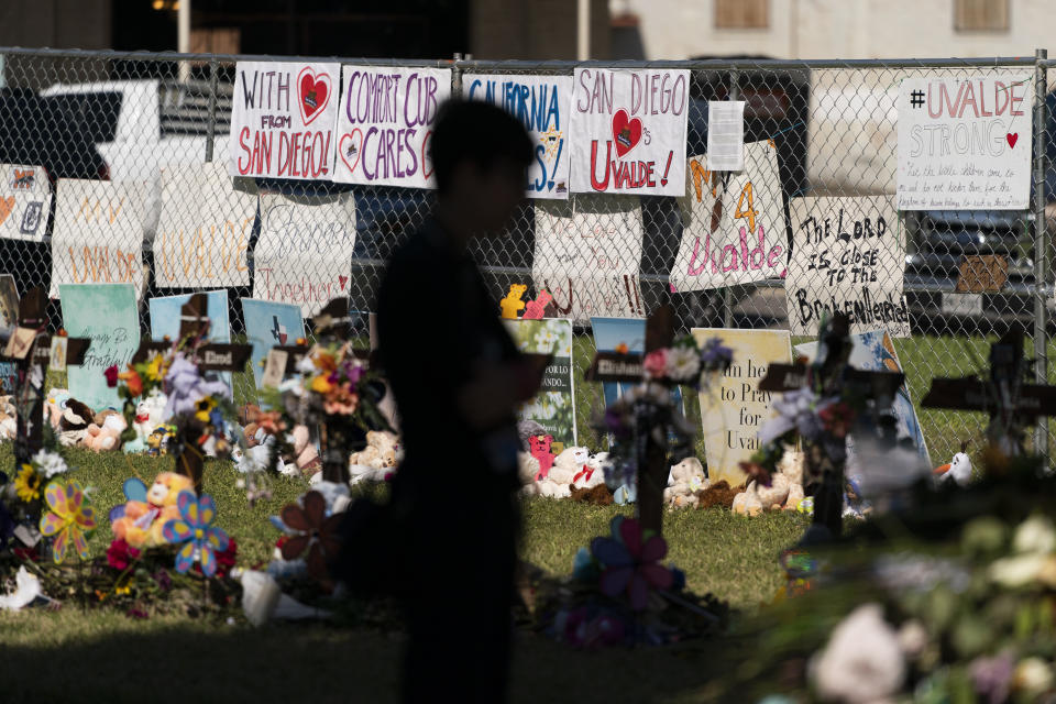 A woman visits a memorial honoring the victims killed in last week's elementary school shooting in Uvalde, Texas, Friday, June 3, 2022. It's hard to say exactly when some Texas educators began to feel like they were under siege, but the massacre of 19 students and two teachers at Robb Elementary School is only the latest, horrific episode in a string of events dating back years. (AP Photo/Jae C. Hong)