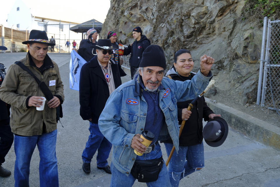 Eloy Martinez, who took part in the Native American occupation, raises a fist while making his way to ceremonies marking the 50th anniversary of the occupation on Alcatraz Island, Wednesday, Nov. 20, 2019, in San Francisco. About 150 people gathered at Alcatraz to mark the 50th anniversary of a takeover of the island by Native American activists. Original occupiers, friends, family and others assembled Wednesday morning for a program that included prayer, songs and speakers. (AP Photo/Eric Risberg)