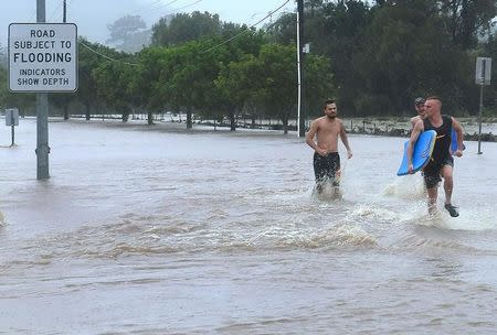 Locals run through floodwaters after heavy rain associated with Cyclone Debbie in the the Gold Coast suburb of Mudgeeraba in Queensland, Australia, March 30, 2017. AAP/Dave Hunt/via REUTERS