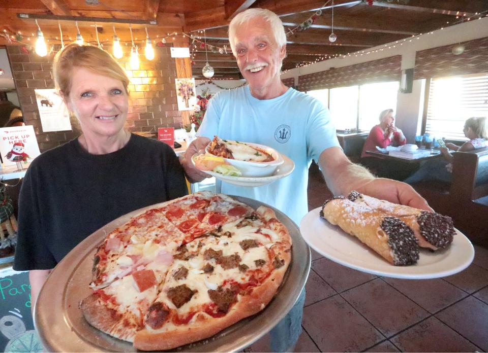 Karen and Scott Chase, owners of Paradise Pizza, hold a selection of pizza from the pizza bar, homemade lasagna and homemade cannolis. "Is it perfect yet? No. But we make our own sauce, we make our own lasagna, coleslaw, potato salad," said Scott.