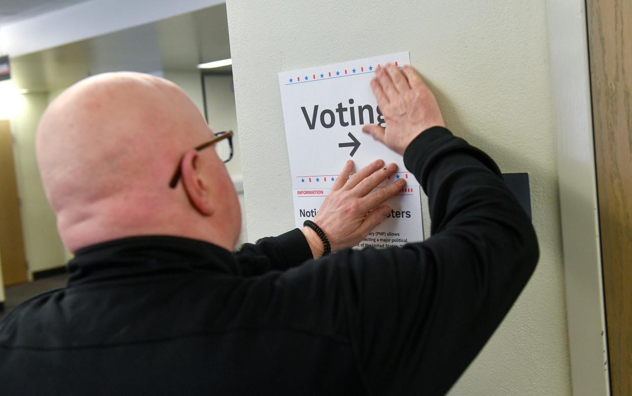 Election judge Dave Warne positions a sign directing voters to the polling place during the Minnesota presidential primary election Tuesday, March 3, 2020, at St. Cloud State University. 