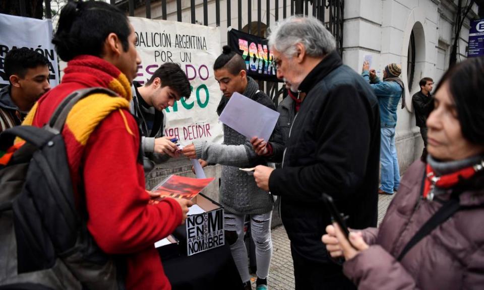 People sign forms to renounce their religious affiliation to the Catholic church outside the Argentine Episcopal Conference in Buenos Aires on 24 August, 2018. 