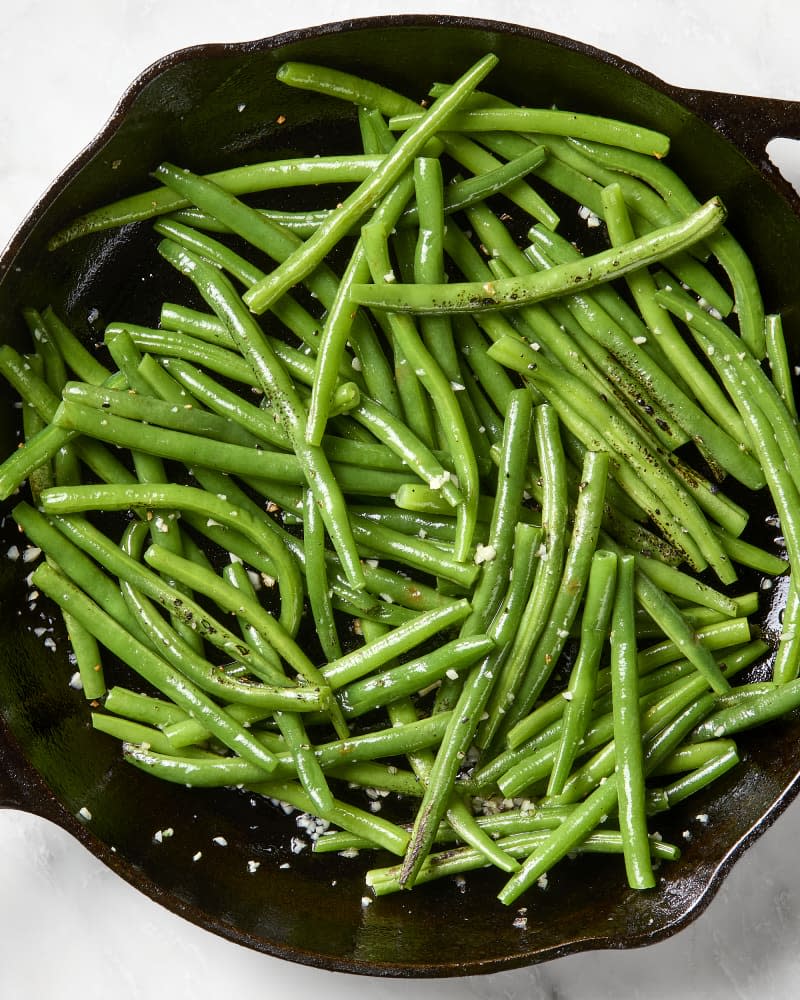 overhead shot of green beans and garlic in a cast iron pan