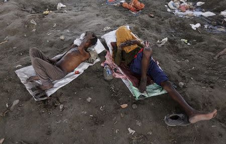 People sleep on the Yamuna river bed under a railway bridge during a hot summer day in the old quarter of Delhi, India, May 31, 2015. REUTERS/Adnan Abidi