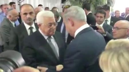 A still image taken from a handout video shows Palestinian President Mahmoud Abbas shaking hands with Israel's Prime Minister Benjamin Netanyahu at the funeral of former Israeli President Shimon Peres in Jerusalem September 30, 2016. REUTERS/Handoutl via Reuters TV