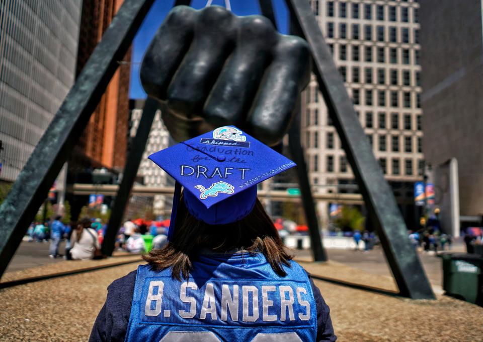Kayla Wilson, of West Bend, Wisconsin, wears her graduation cap as she skipped walking across the stage for her graduation at Michigan Tech, where she is receiving a master's in manufacturing engineering, to be at the NFL draft in downtown Detroit at Hart Plaza on Friday, April 26, 2024. “Football is big with me and my mom,” said the Detroit Lions season ticket holder. “I guess I got my priorities straight.”