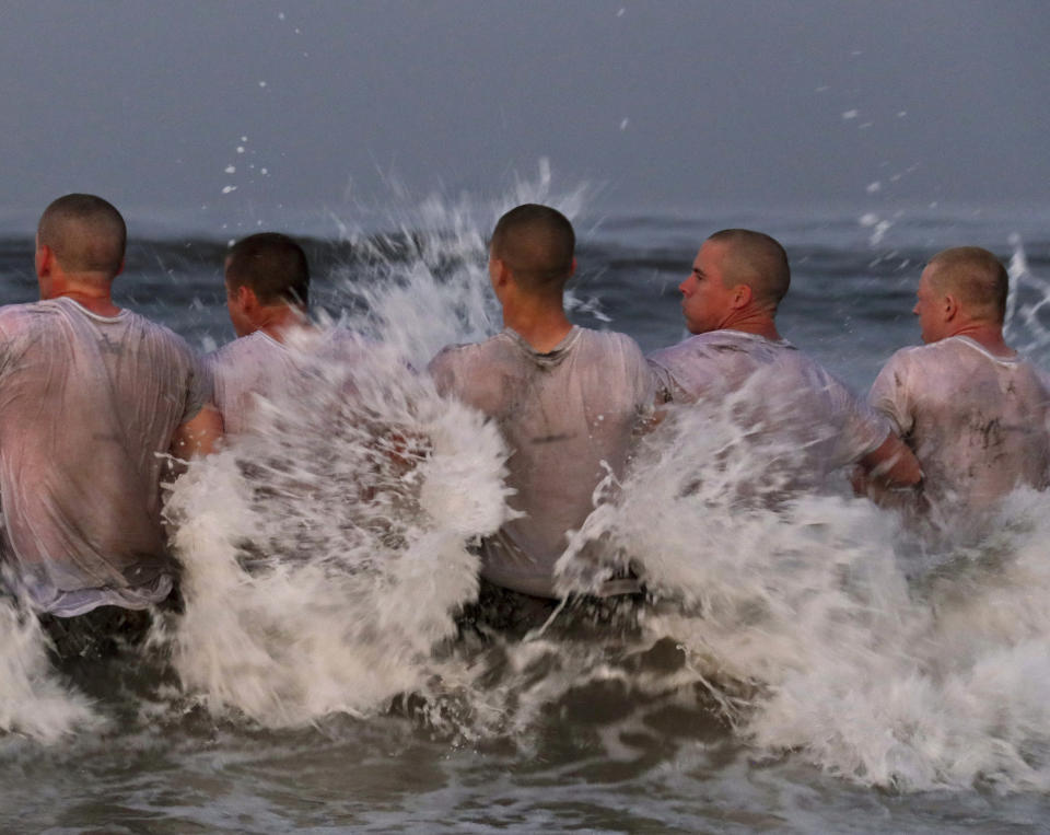 This Monday May 4, 2020, photo provided by the U.S. Navy shows SEAL candidates participating in "surf immersion" during Basic Underwater Demolition training at the Naval Special Warfare (NSW) Center in Coronado, Calif. Navy SEAL recruits and their instructors are being tested for the coronavirus as the candidates in one of the military's most grueling programs return to training with new social distancing guidelines, a top official said Tuesday, May 5, 2020. (MC1 Anthony Walker/U.S. Navy via AP)