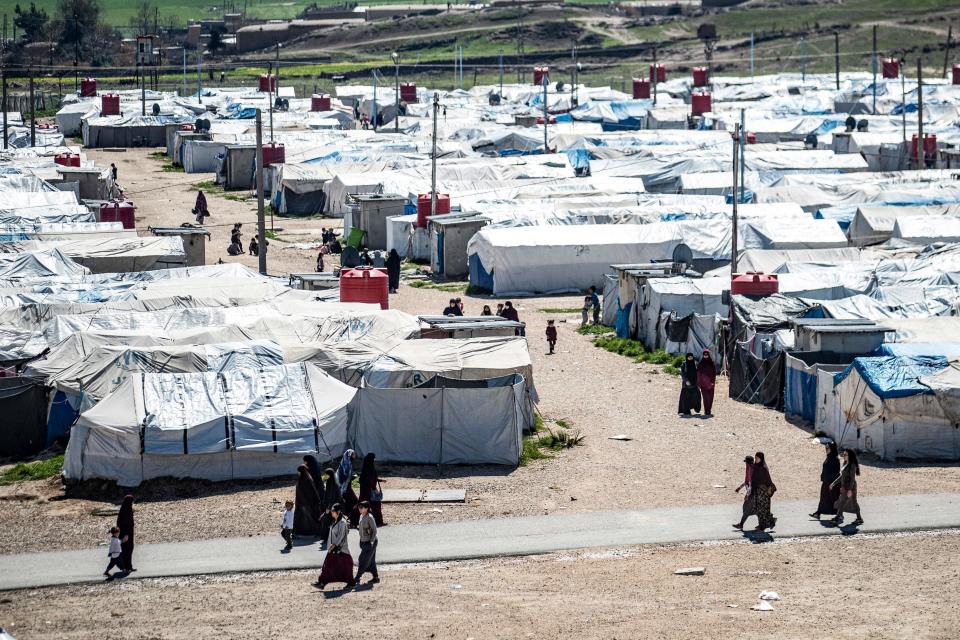 Women and children walk at Camp Roj, where relatives of people suspected of belonging to the Islamic State (IS) group are held, in the countryside near al-Malikiyah (Derik) in Syria's northeastern Hasakah province, on March 28, 2021. - Roj, one of two Kurdish-run displacement camps housing foreign family members of suspected IS fighters, is smaller and better guarded than its overcrowded counterpart Al-Hol, which has been rocked by assassinations and breakout attempts in recent months. (Photo by Delil SOULEIMAN / AFP) (Photo by DELIL SOULEIMAN/AFP via Getty Images)