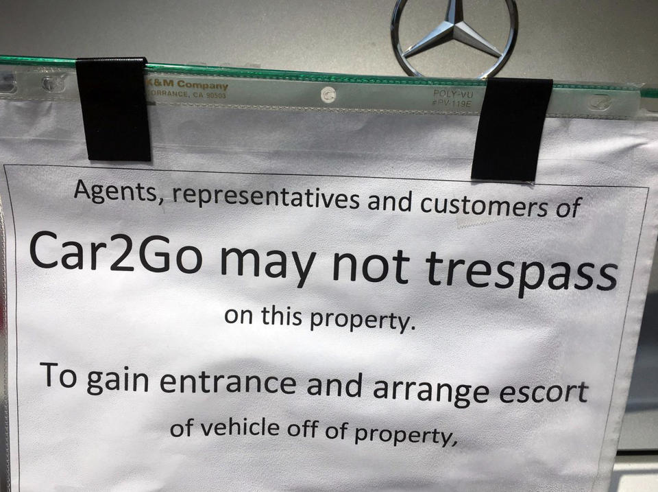 This undated photo provided by KOMO News shows a notice attached to a car-share vehicle parked at a Seattle duplex. Dan Smith took exception to the car2go Mercedes that has been parked there since May 17, 2019. He says he doesn't know who parked the car there, but it wasn't one of the tenants. By the next day he had erected the barricade, preventing other customers from using the vehicle. He wants Share Now, which operates car2go, to pay storage fees. The company says it won't tolerate having its vehicle held for ransom. (KOMO News via AP)