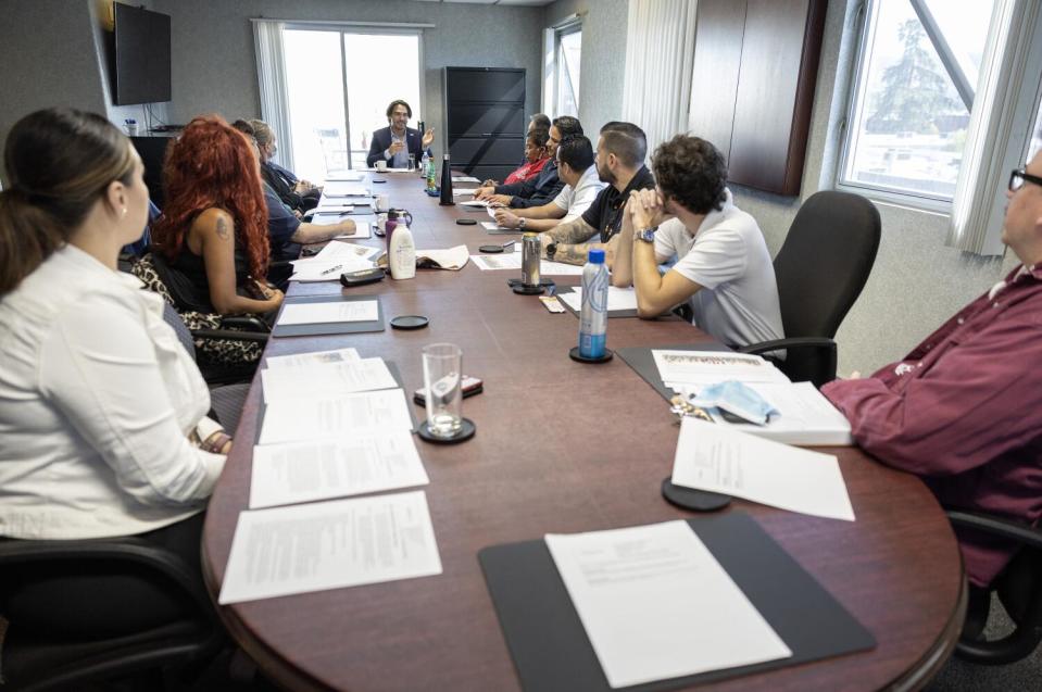 People sit around a conference table, with papers spread out in front of them.