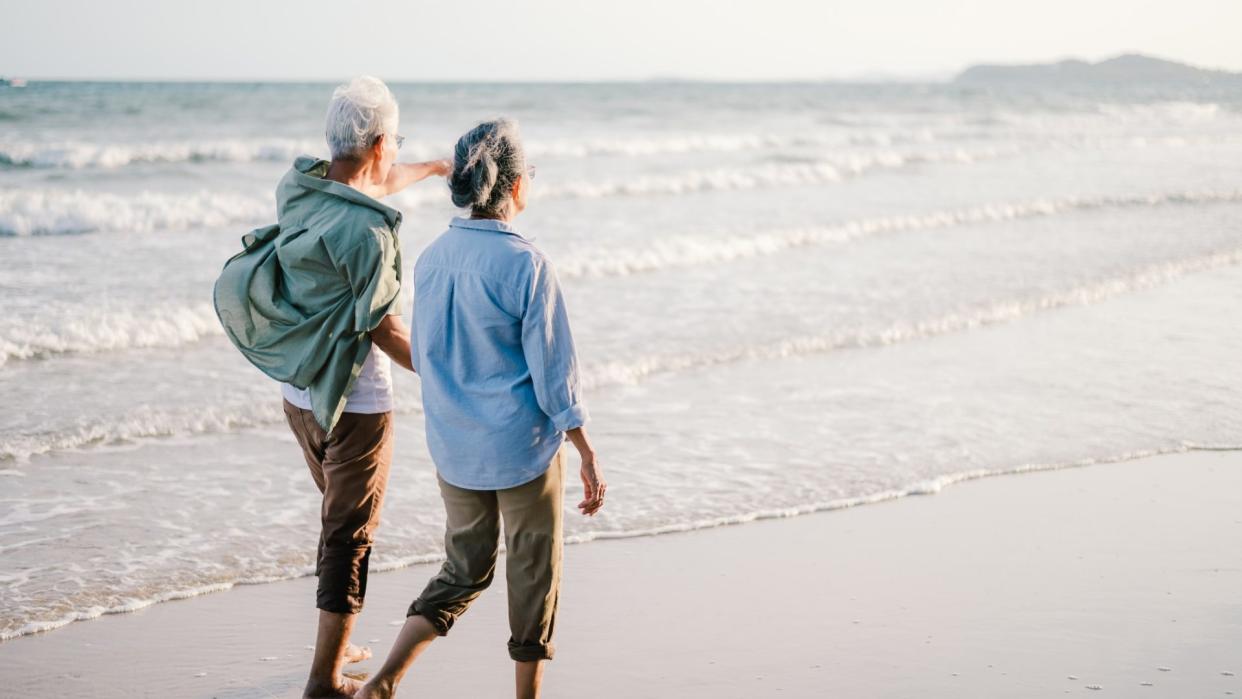 Couple walking along a beach. (Getty Images)